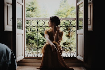 woman sitting on floor near window at daytime