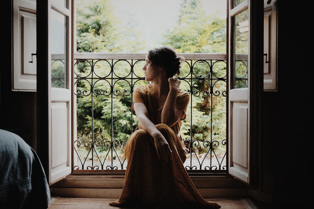 Mujer sentada en el suelo cerca de la ventana durante el día