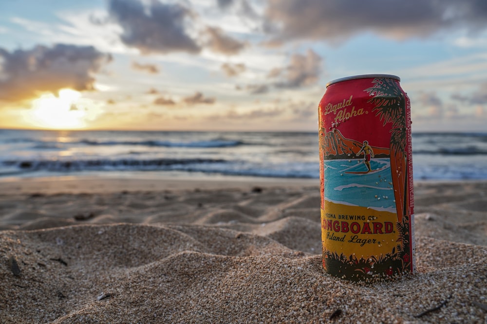 Longboard beverage can on sand by the beach during day