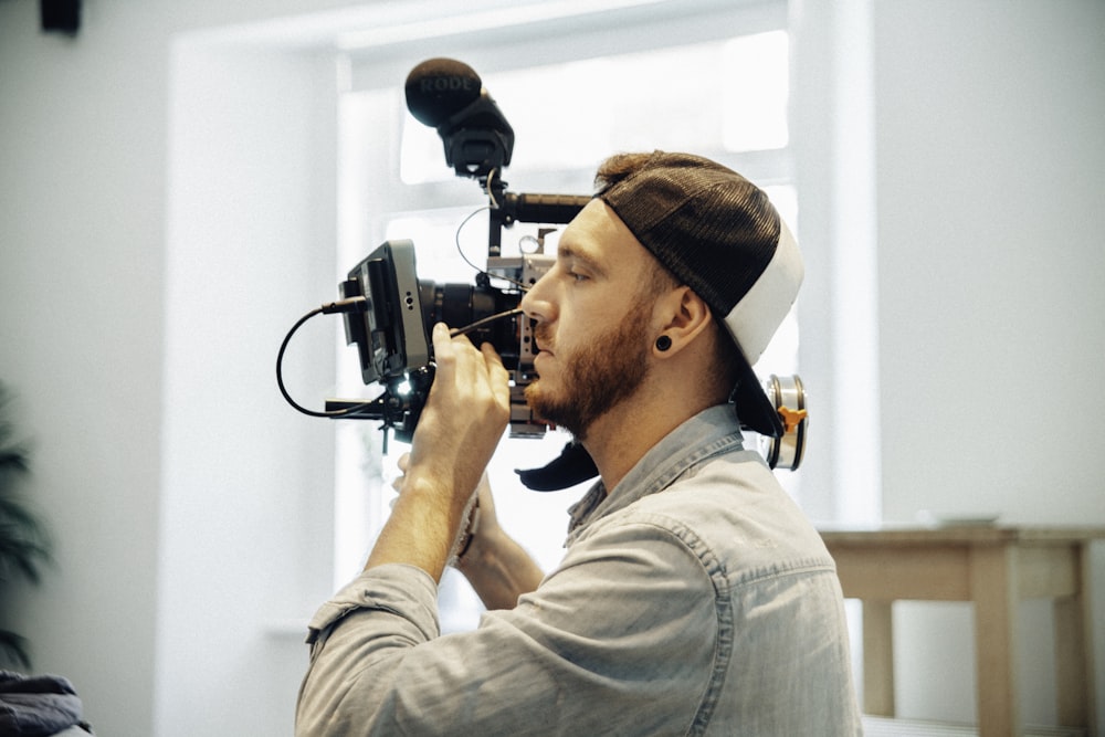 man wearing chambray shirt holding shoulder-mount camera