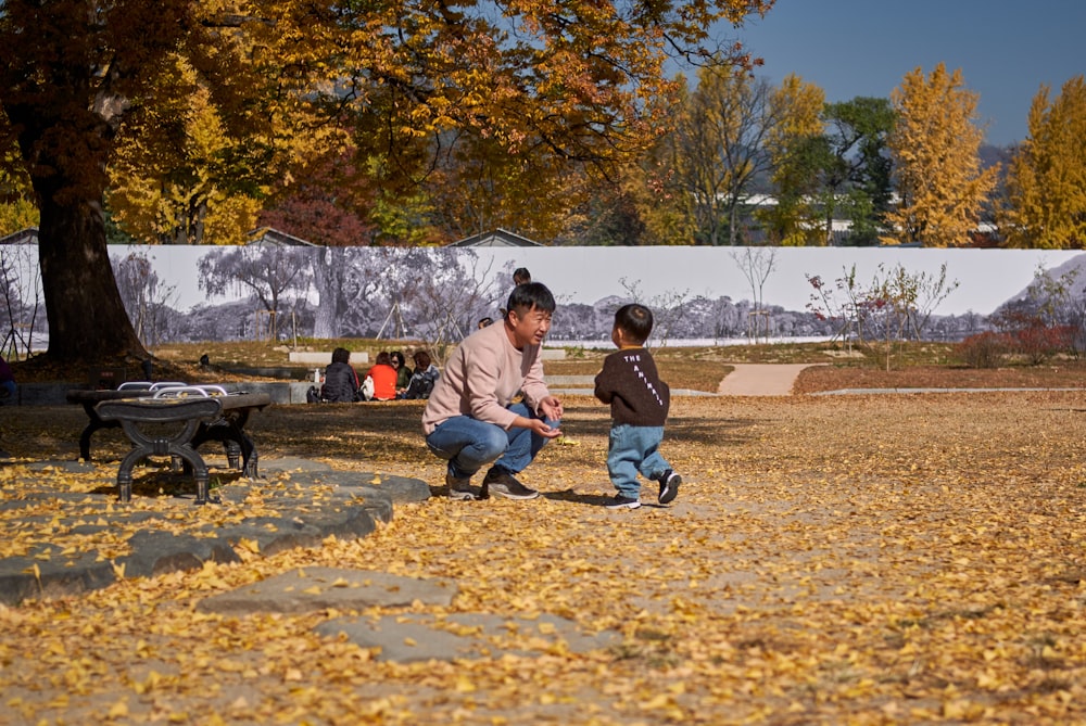 man crouching in front of boy running