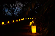 A softly lit pathway lined with candles leading to a secluded spa villa surrounded by deep earthy brown wooden elements.