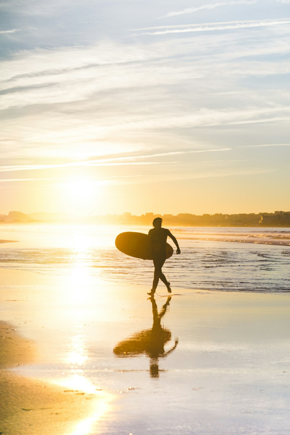 hombre sosteniendo la tabla de surf en la orilla del mar