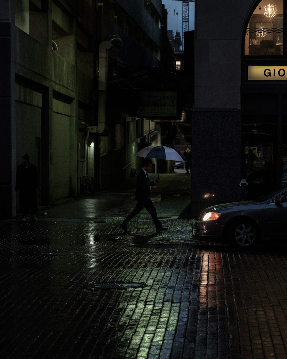 homem atravessando estrada com guarda-chuva durante a noite