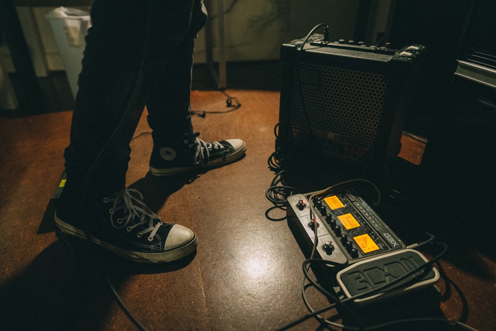 man standing beside guitar amplifier and guitar pedal distortion