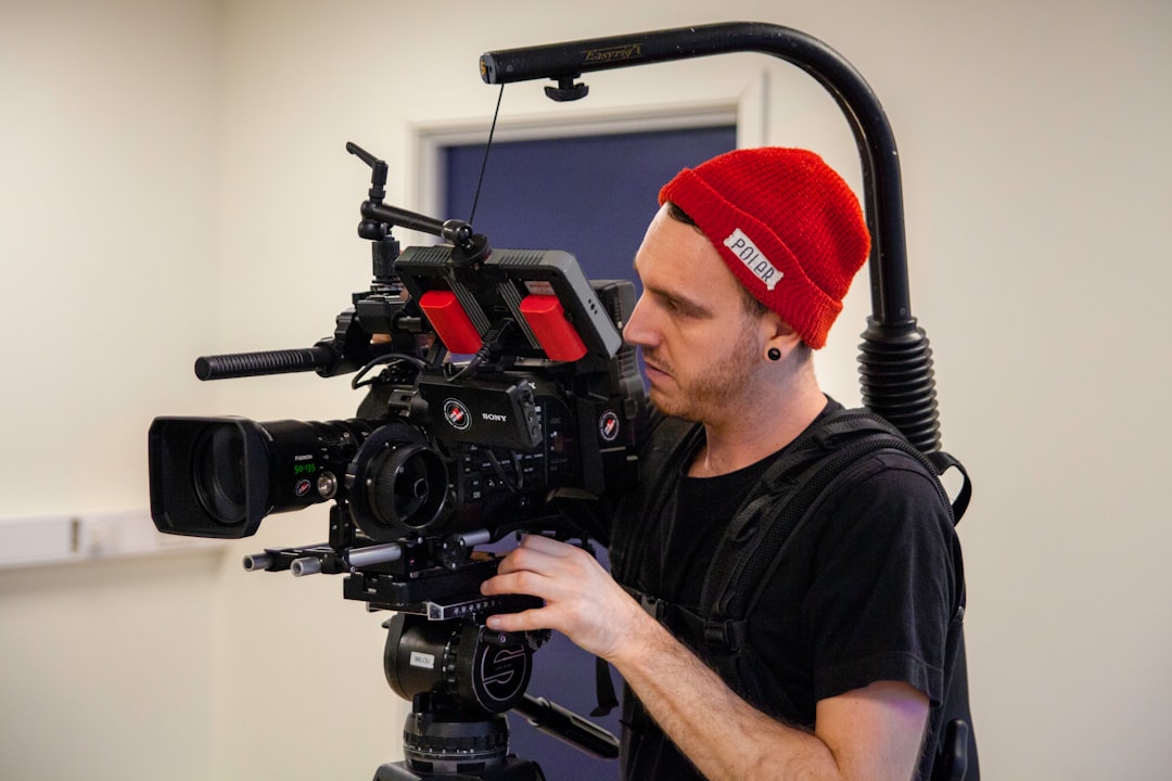 man in black shirt carrying movie camera with stabilizer,