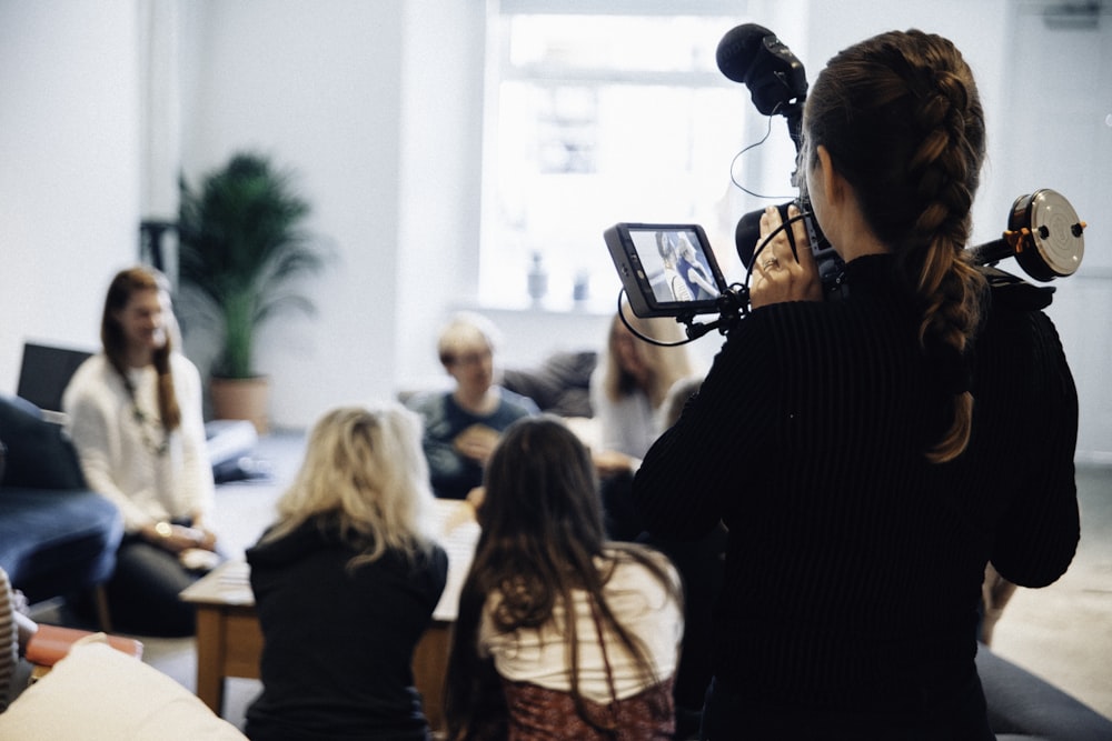 woman holding camera standing near people