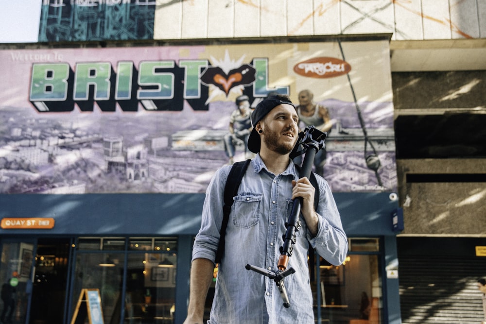 man holding camera tripod standing near store