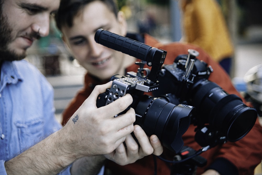 persona che tiene e guarda la fotocamera DSLR nera