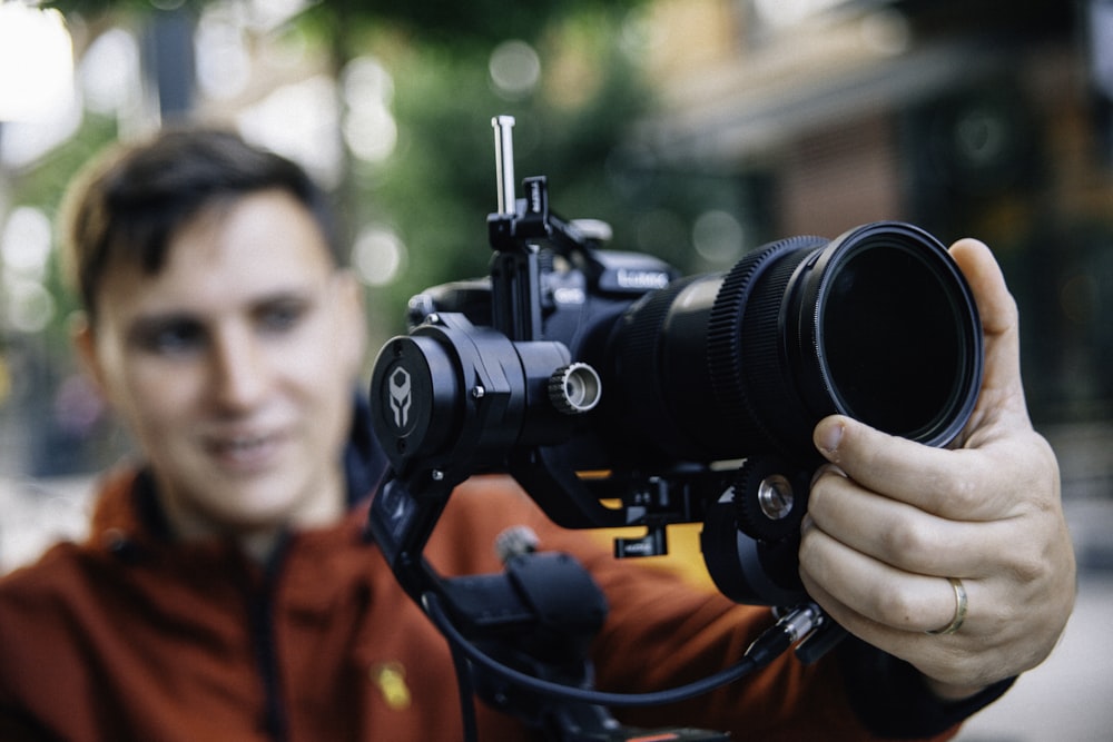 man holding black Canon DSLR camera \during daytime