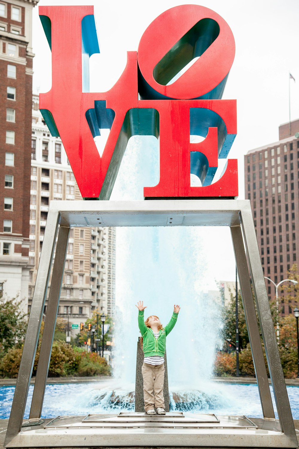 girl standing under love sign near fountain