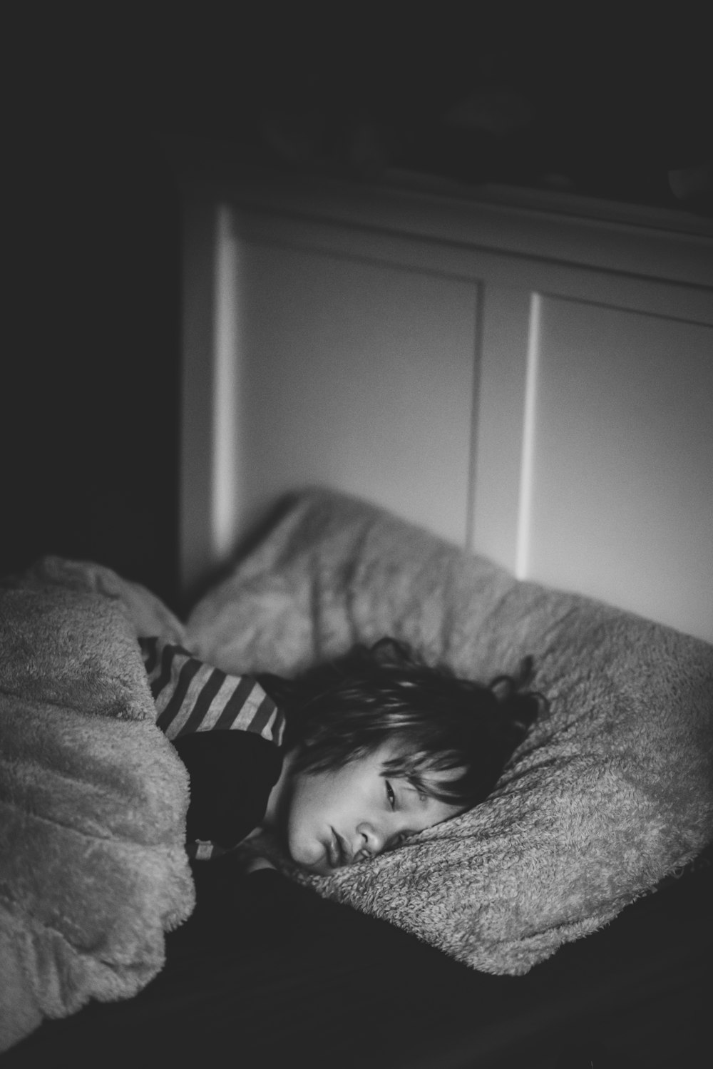 grayscale photography of kid lying on bed