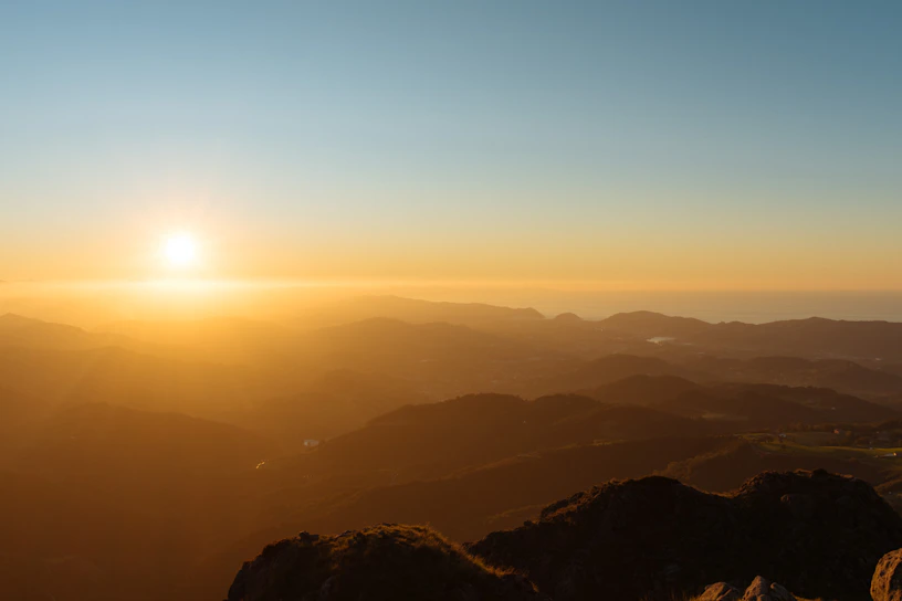 A breathtaking sunrise view from the summit of Mount Kilimanjaro, with golden light spilling over the rugged landscape.