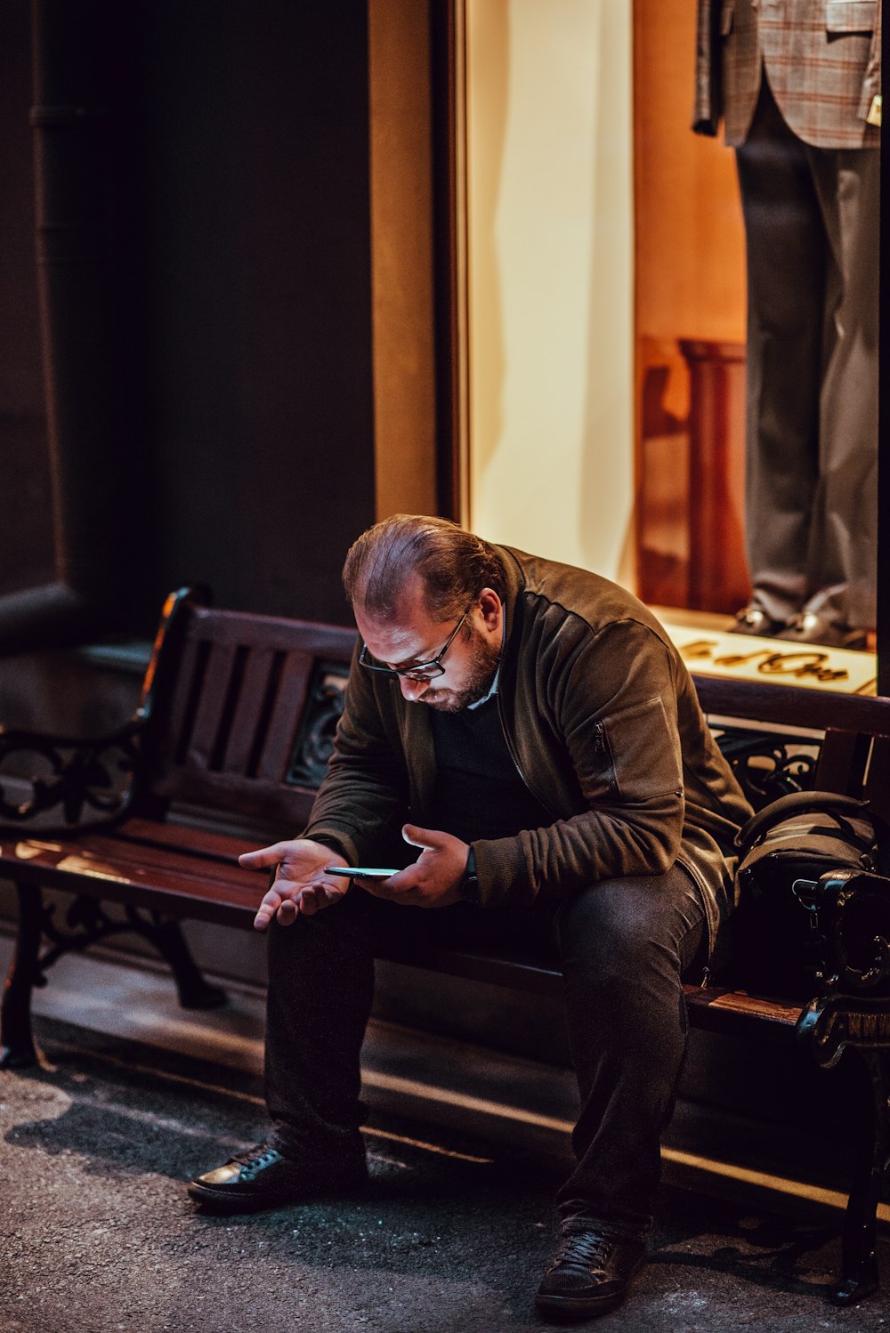 man sitting on bench using smartphone
