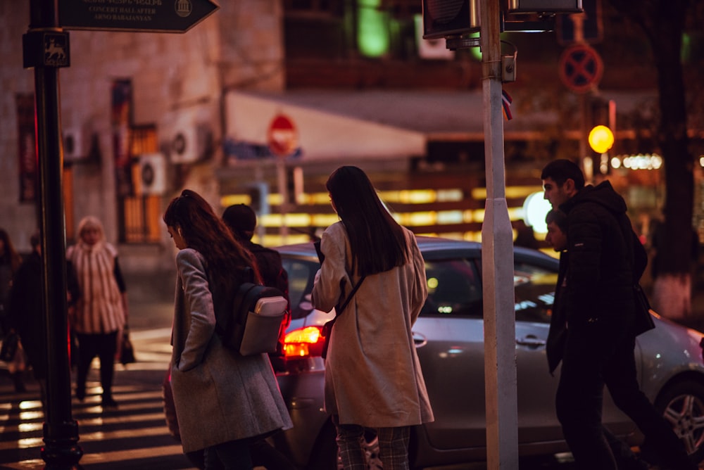 people passing on pedestrian lane near gray 5-door hatchback at night time