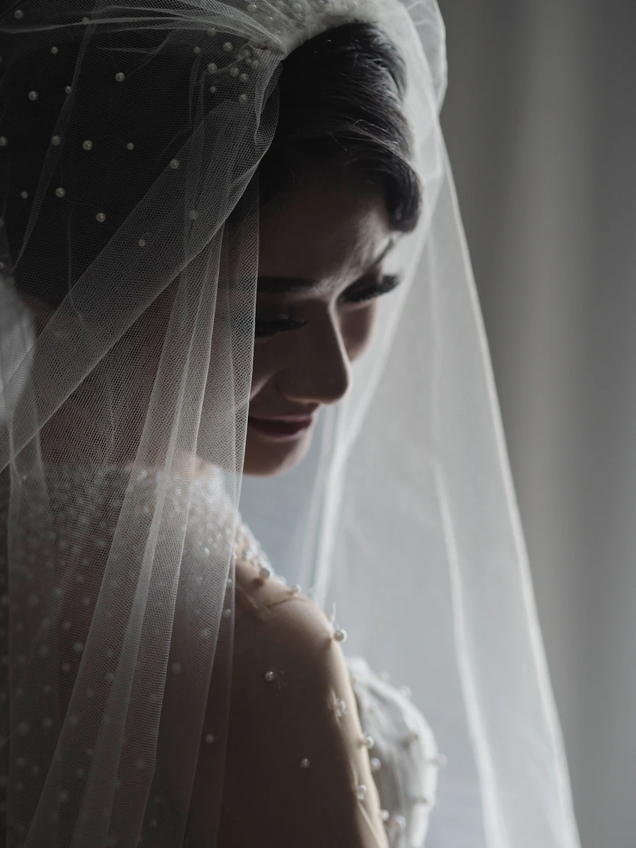 An editorial portrait of a bride in a sheer wedding gown, soft interior light