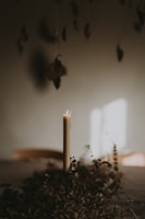 Close-up of a candle with dried flowers and embedded natural stones glowing softly.