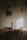 A single lit candle casting flickering shadows on a textured peat brown cloth with scattered dried botanicals.
