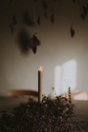 Soft candlelight illuminating torn paper edges and delicate eucalyptus leaves on a rustic wooden table.