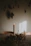 A softly lit candle on a textured linen cloth surrounded by dried florals in a cozy corner.