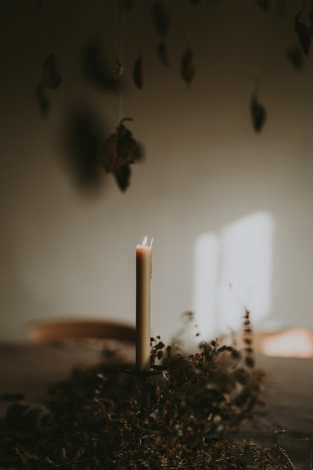 white pillar candle lighted on brown shrubs