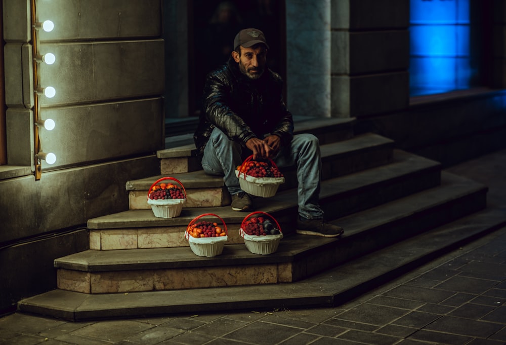 man sitting on stairs holding basket at night time