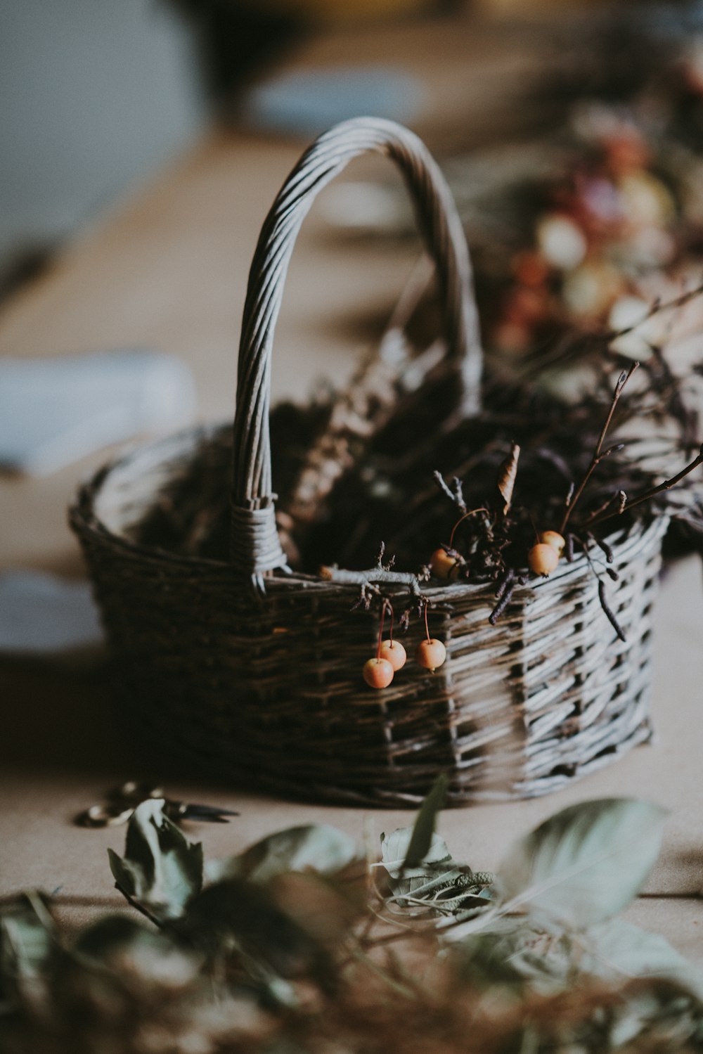 round yellow fruit with twigs in wicker brown basket on top of table inside room