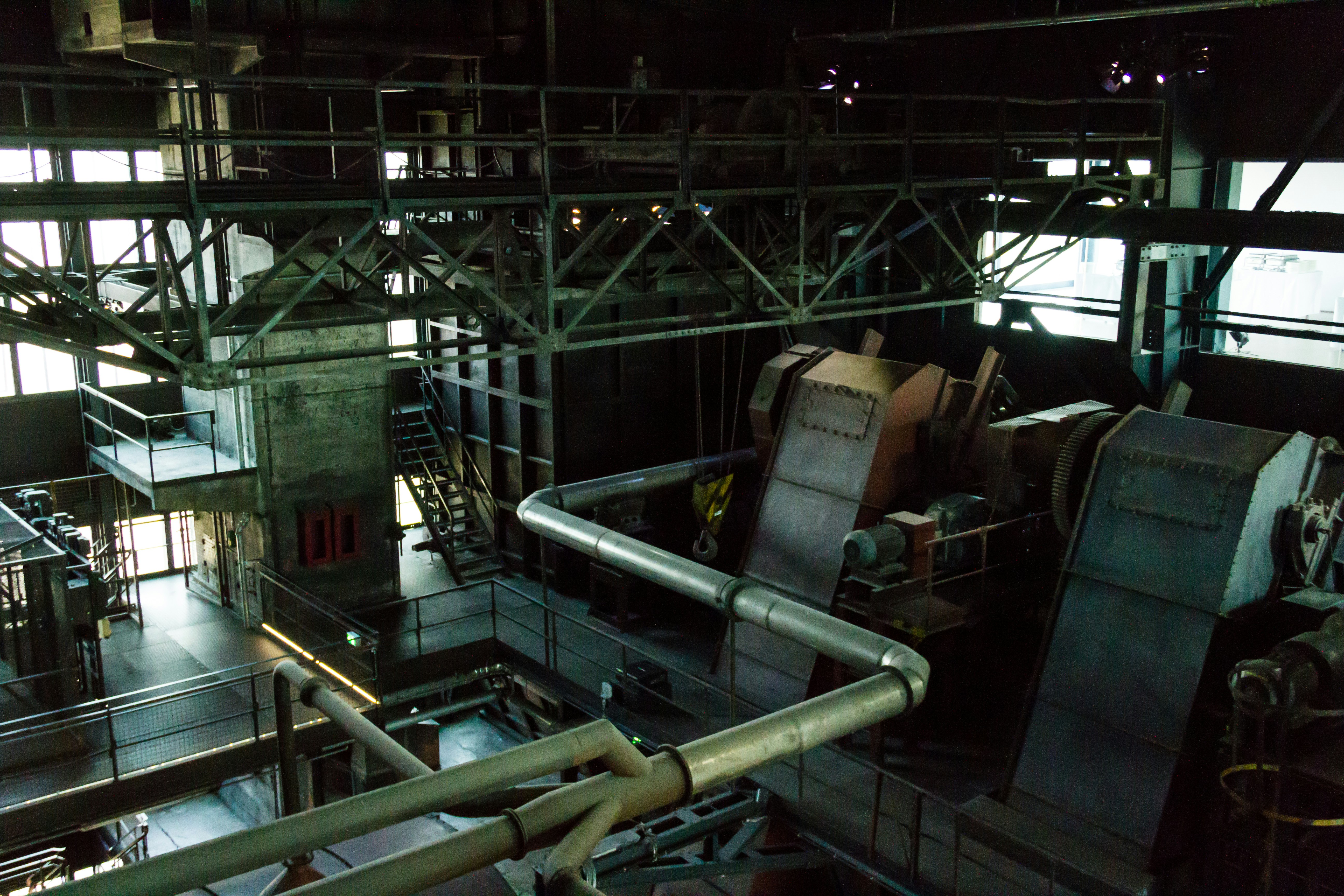 Dark industrial CQB arena with steel catwalks and tight corridors, dramatic overhead lighting, high contrast