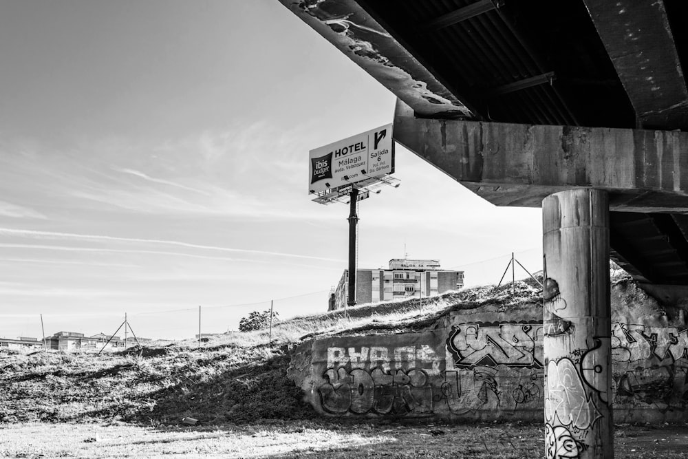 greyscale photography of bridge underpass and billboard