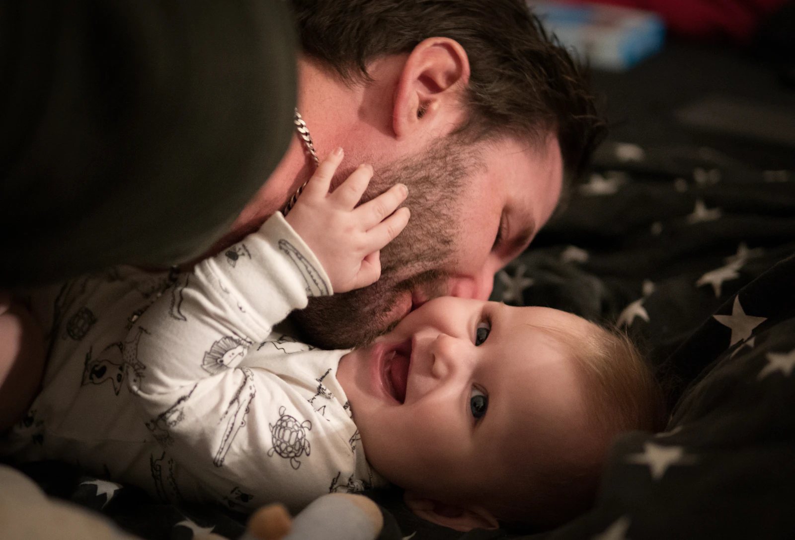 A father and his laughing baby sharing a playful, affectionate face-to-face moment