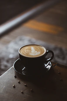 A steaming cup of coffee with intricate latte art, set against a backdrop of natural light and Chiapas-inspired decorations.