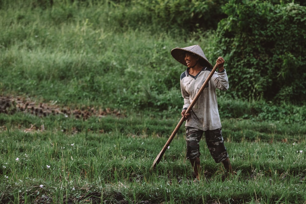 man standing on grass holding stick at daytime