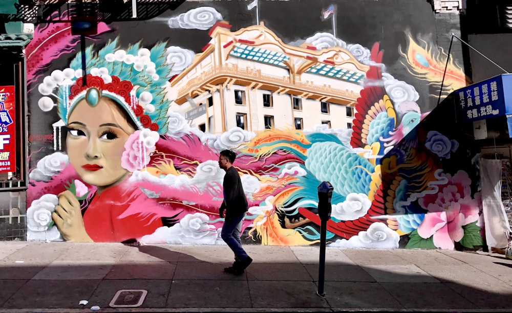 man standing in front of female mural