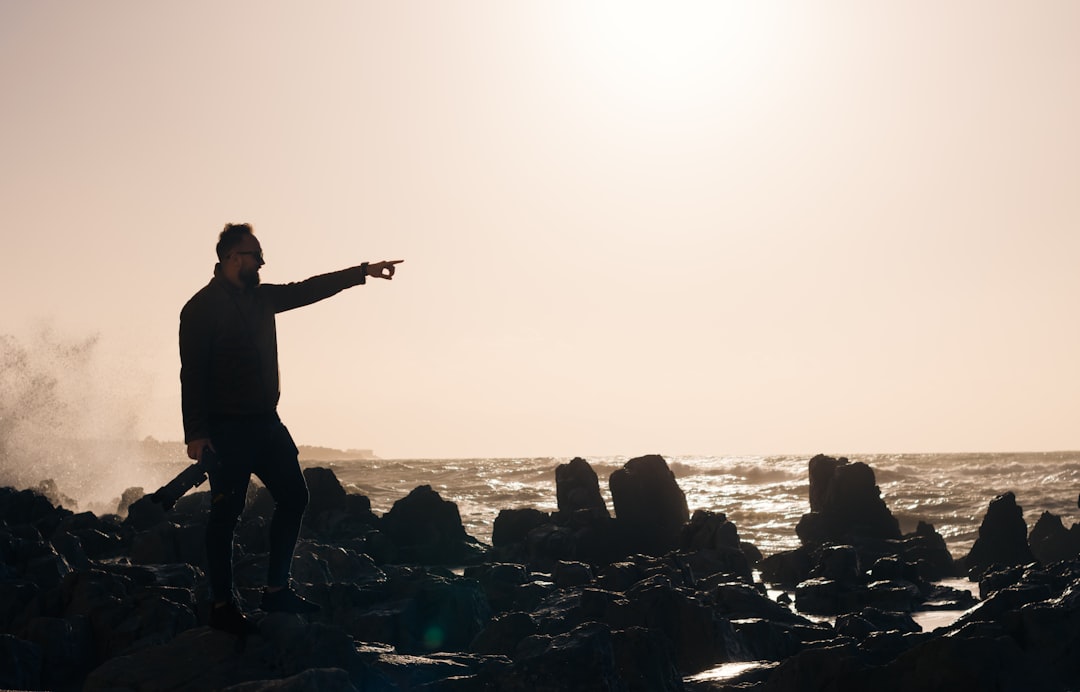 man standing on rock formation during daytime