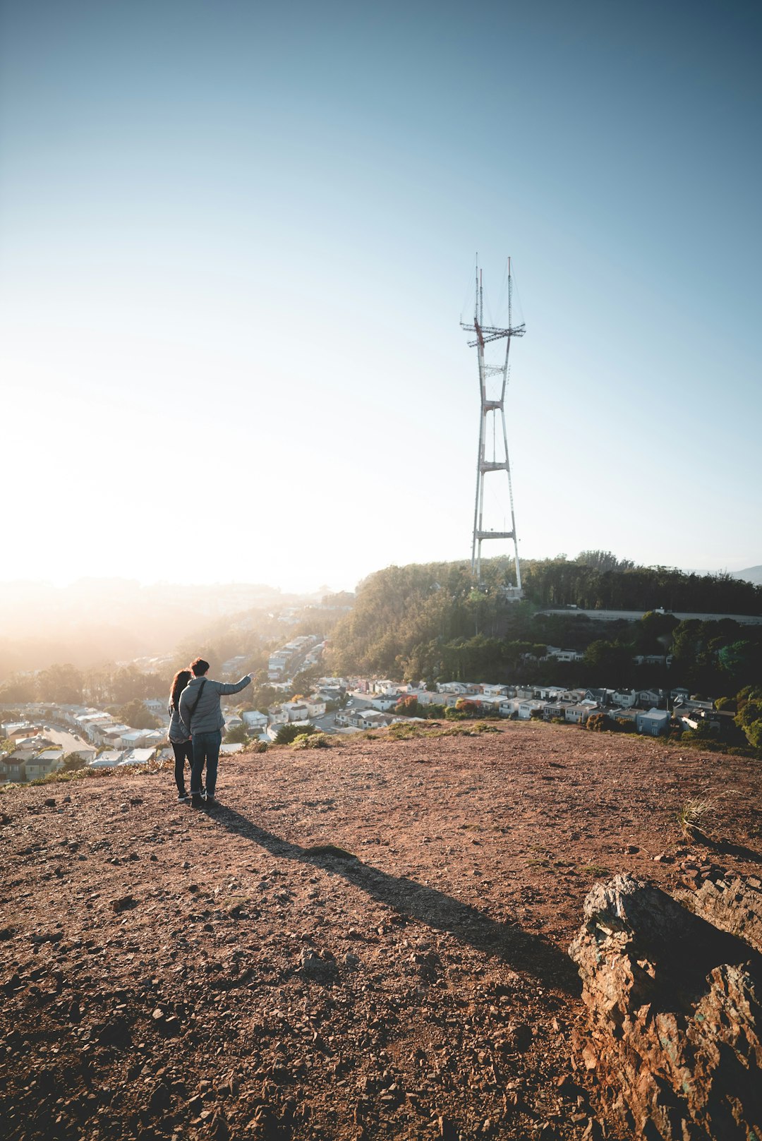 man and woman standing on cliff looking at village