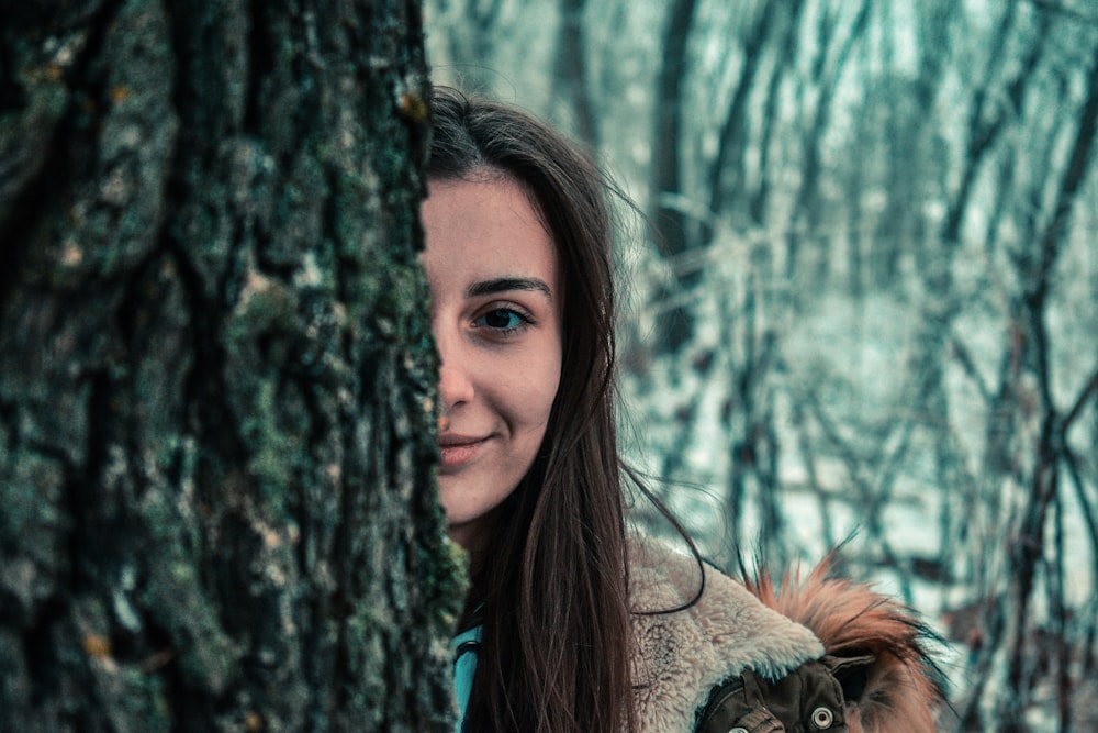 woman standing behind gray tree