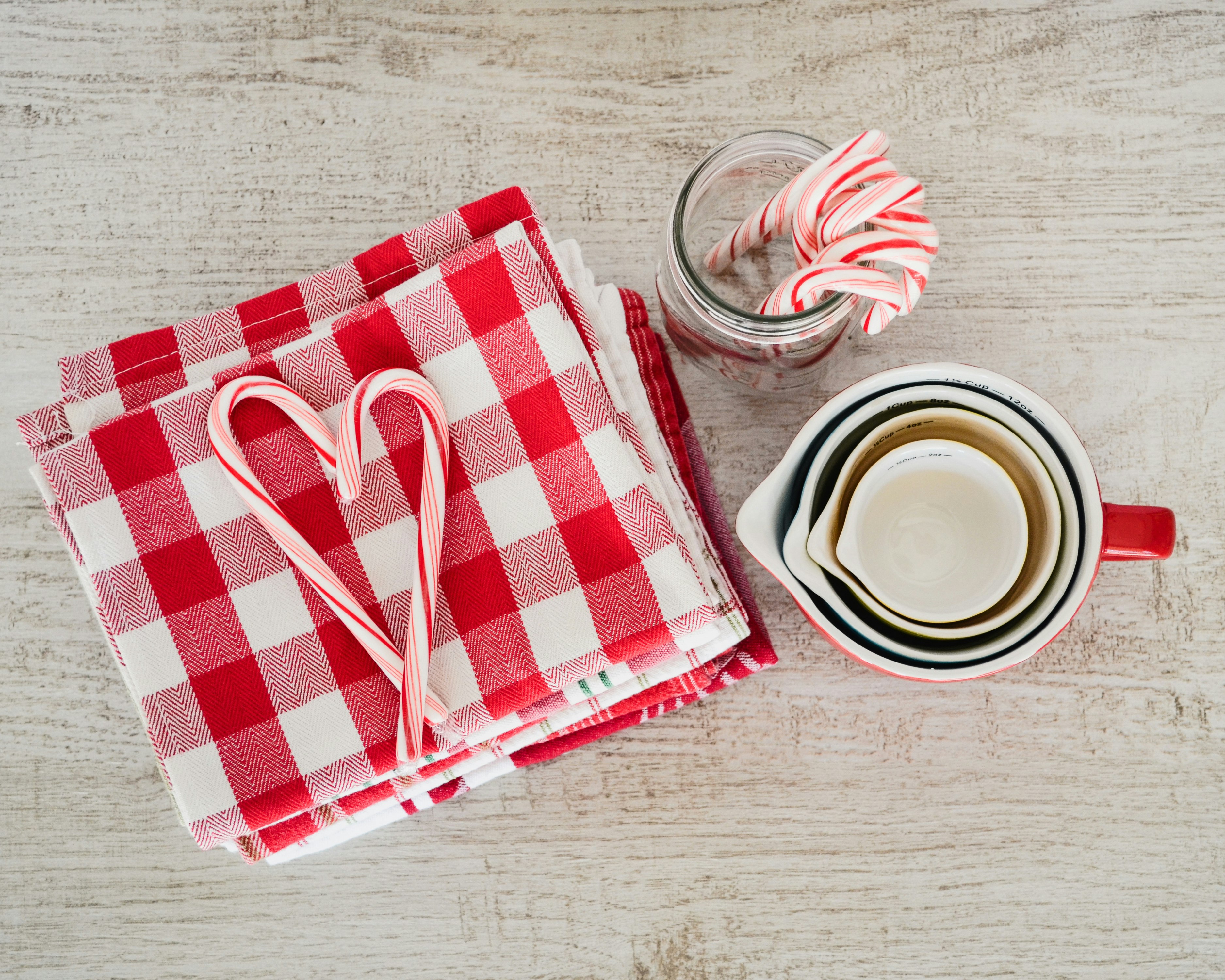 white ceramic mugs beside red and white checked textile