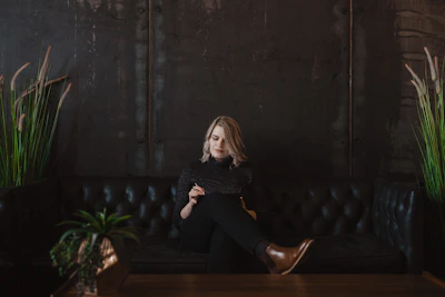 A person happily reviewing their budget on a tablet, surrounded by plants and soft dark mode ambiance.