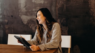 woman sitting around table holding tablet