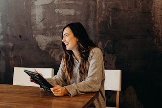 woman sitting around table holding tablet