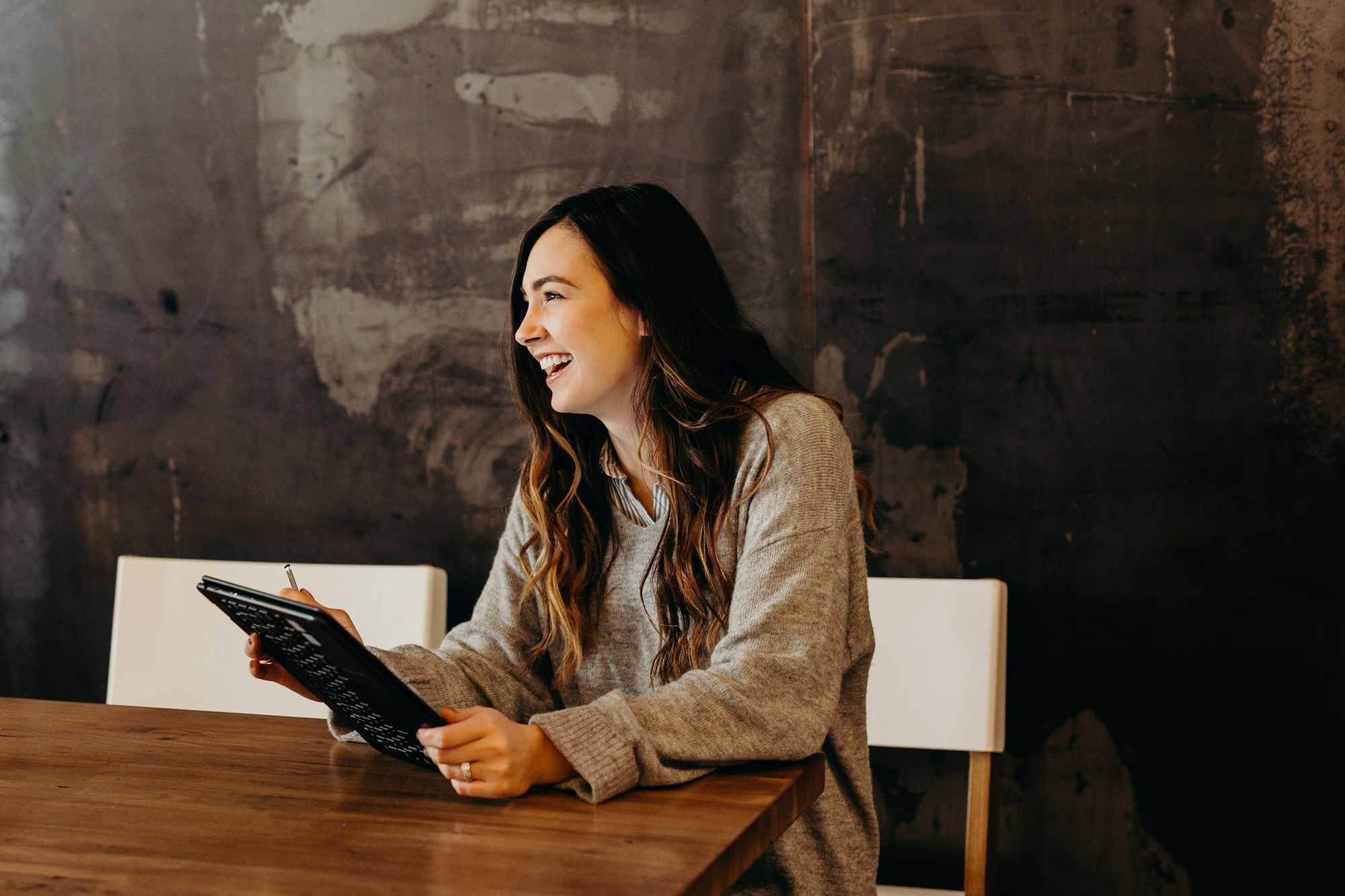 Image of a woman smiling while holding a tablet