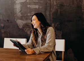 woman sitting around table holding tablet