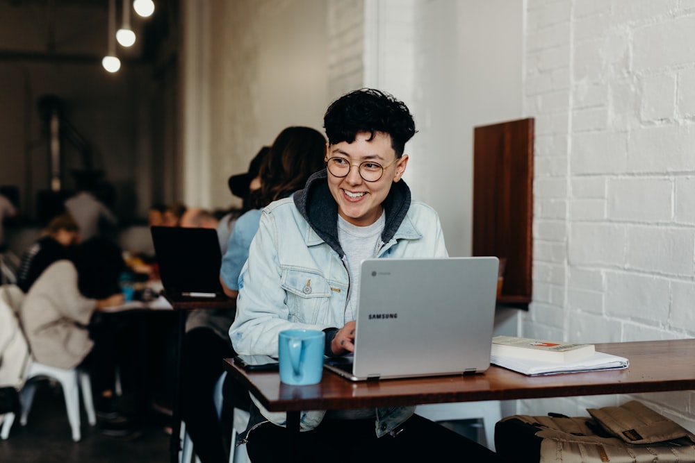 homem sorridente sentado e usando laptop Samsung perto das pessoas