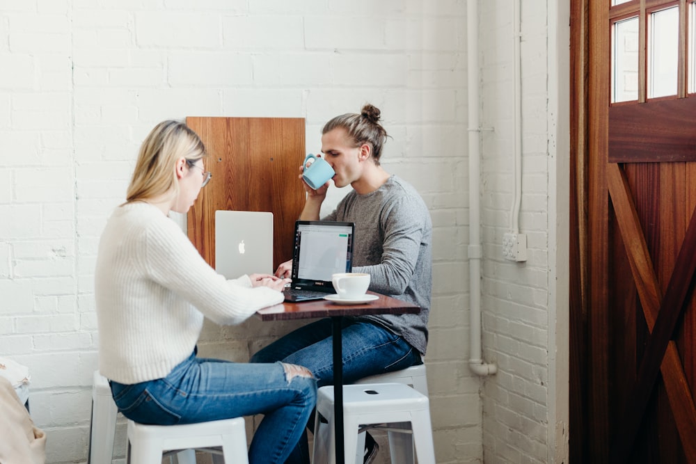 man and woman sitting and using laptops near closed door