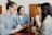 A diverse group of young adults sharing smiles and conversations in a cozy café setting.