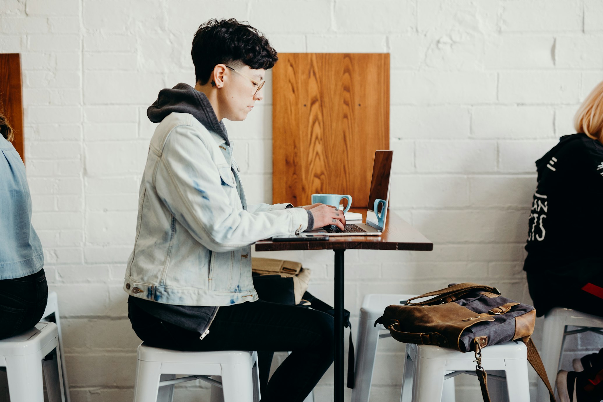 non-binary person working on their laptop in a coffee shop