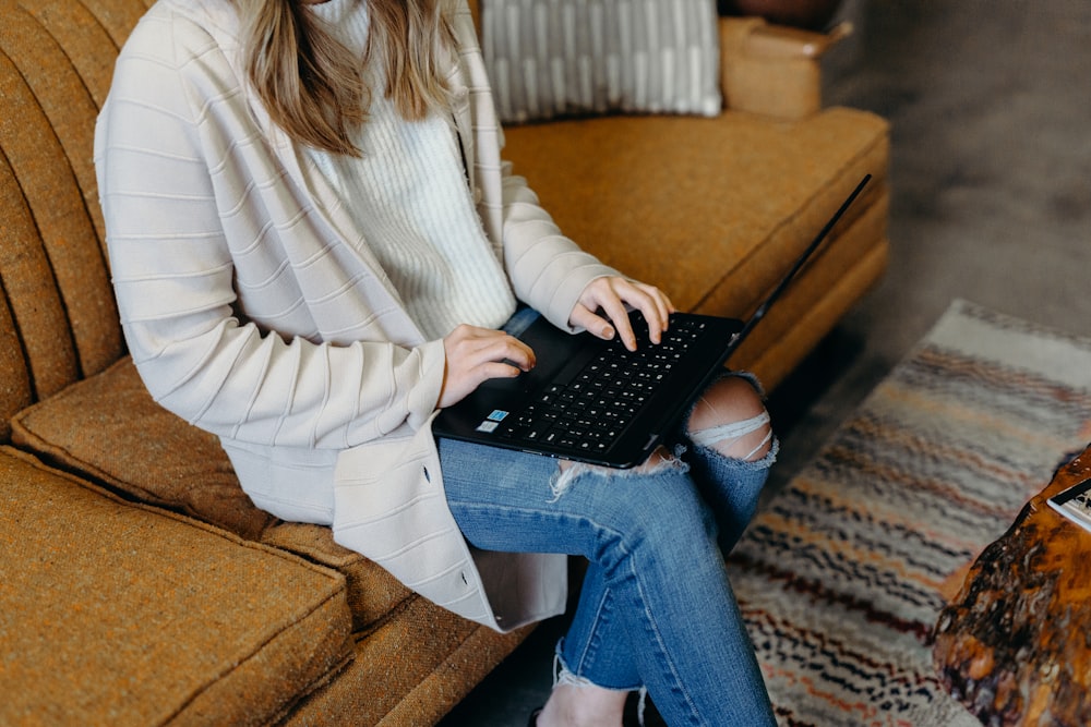 woman sitting on sofa using laptop