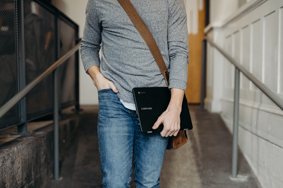 person holding black laptop in walking gesture