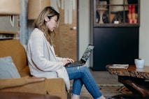 woman using laptop while sitting on sofa chair