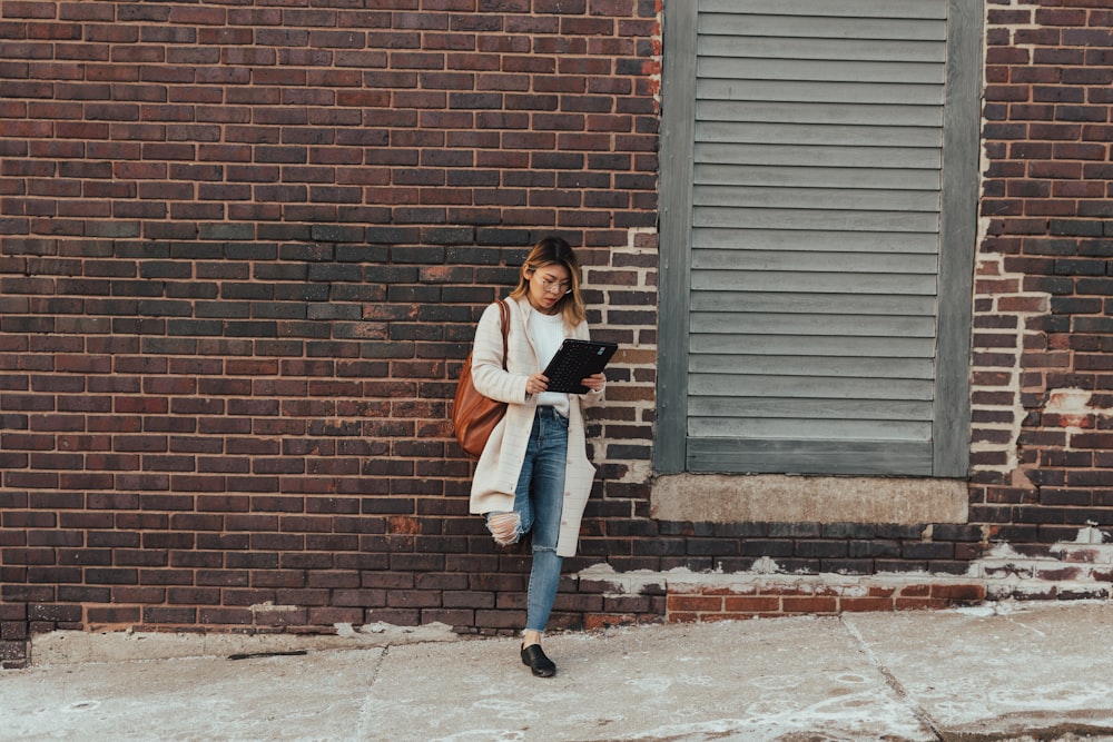 woman wearing blue jeans holding black clipboard